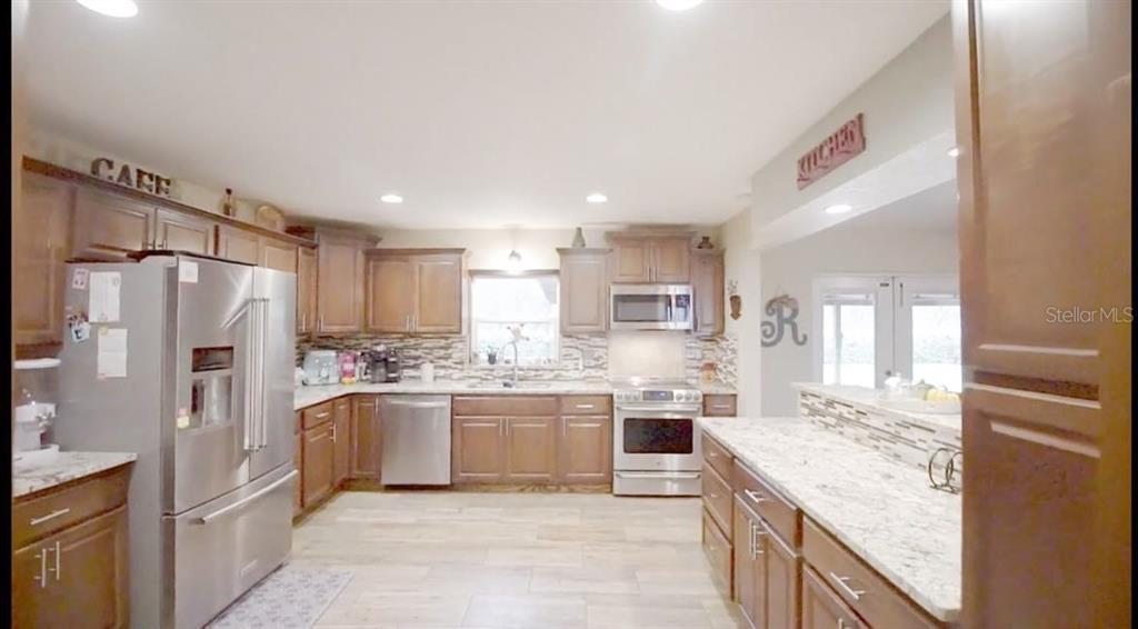 2700 Southeast 157th Lane Road Summerfield, FL 34491 - Photo 7 of 13 a kitchen with stainless steel appliances granite countertop a refrigerator and a stove top oven