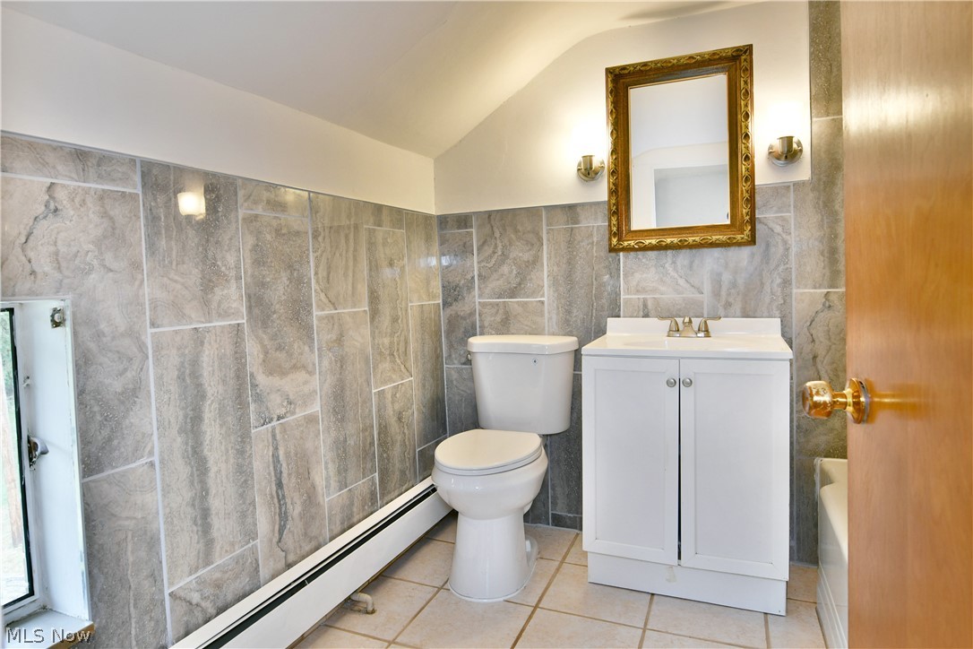 892 Yankee Run Road Masury, OH 44438 - Photo 35 of 50 Bathroom featuring tiled walls, white vanity with integrated sink, gold-framed mirror, and wall-mounted light fixtures