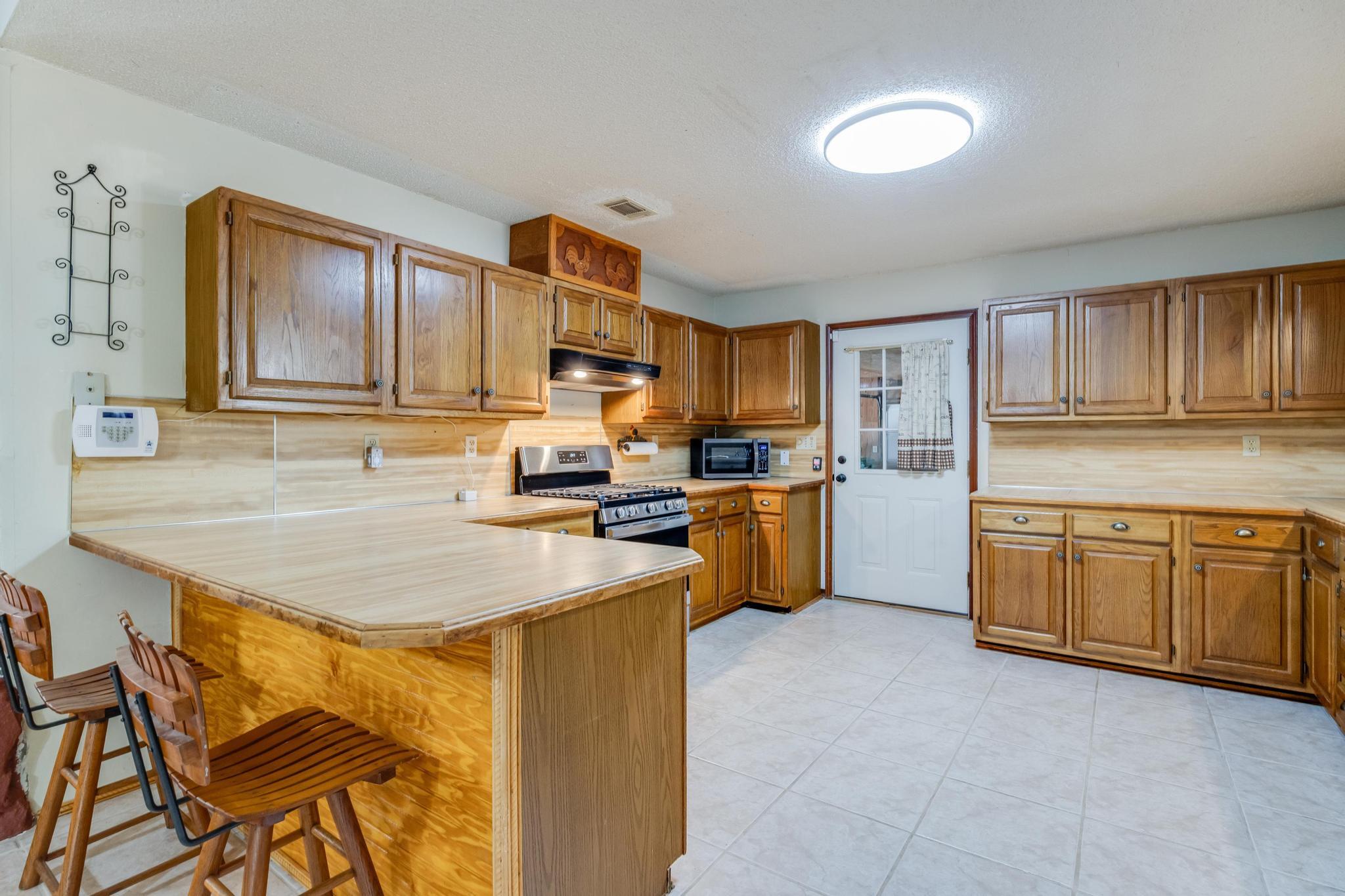 6359 Shangri La Road Crestview, FL 32539 - Photo 12 of 56 a kitchen with kitchen island granite countertop wooden cabinets a sink a stove a oven with dining table and chairs
