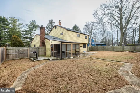 a view of backyard with wooden fence and large trees
