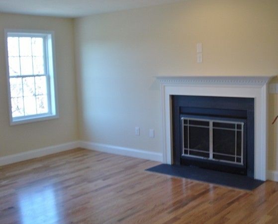 80 Chadwick Road Haverhill, MA 01835 - Photo 6 of 15 an empty room with wooden floor a fireplace and windows