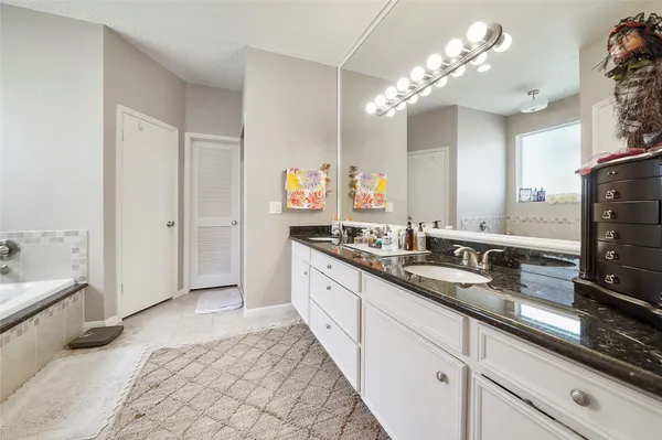 a spacious en suite bathroom with double vanity and a mirror