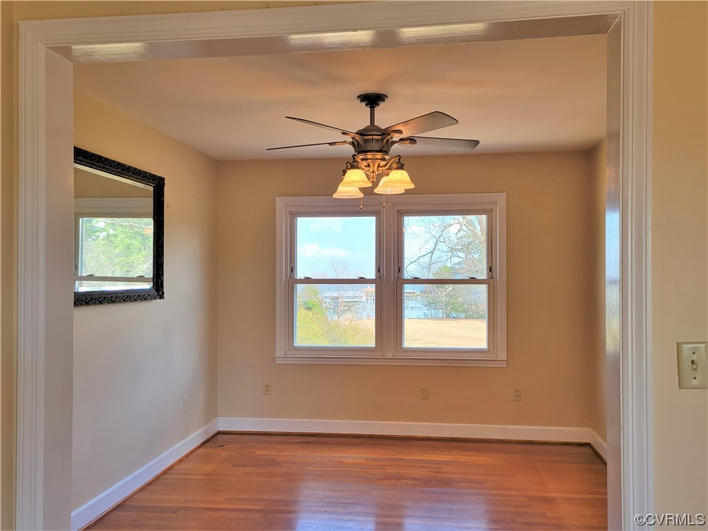 405 Locklies Creek Road Topping, VA 23169 - Photo 20 of 30 an empty room with wooden floor chandelier fan and windows