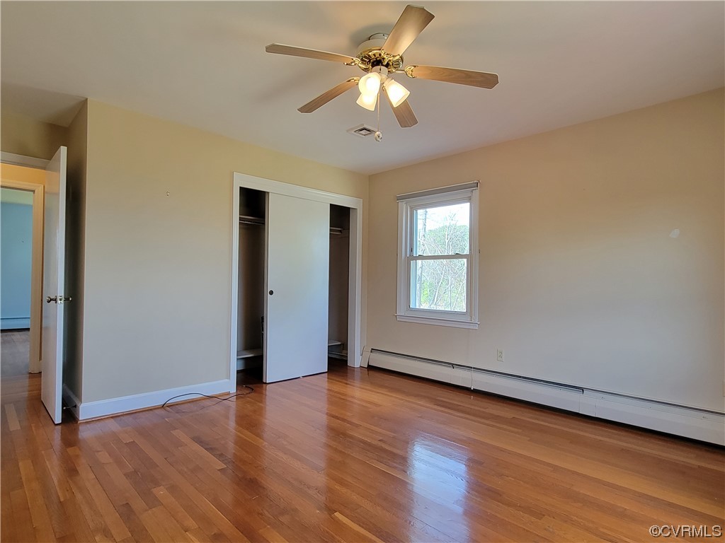 405 Locklies Creek Road Topping, VA 23169 - Photo 24 of 30 an empty room with wooden floor chandelier fan and windows