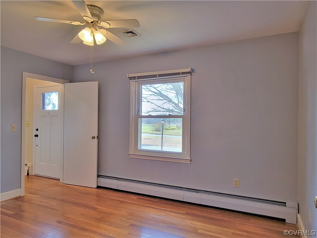 405 Locklies Creek Road Topping, VA 23169 - Photo 25 of 30 an empty room with wooden floor chandelier fan and windows