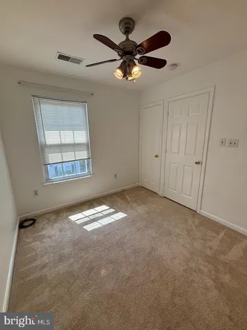 an empty room with windows and fan