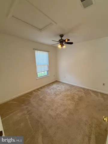 an empty room with a ceiling fan and window
