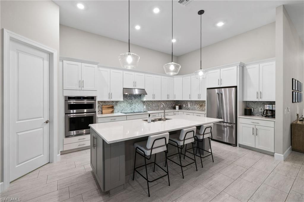 20734 Corkscrew Shores Boulevard Estero, FL 33928 - Photo 11 of 50 a large kitchen with kitchen island a dining table chairs and a refrigerator