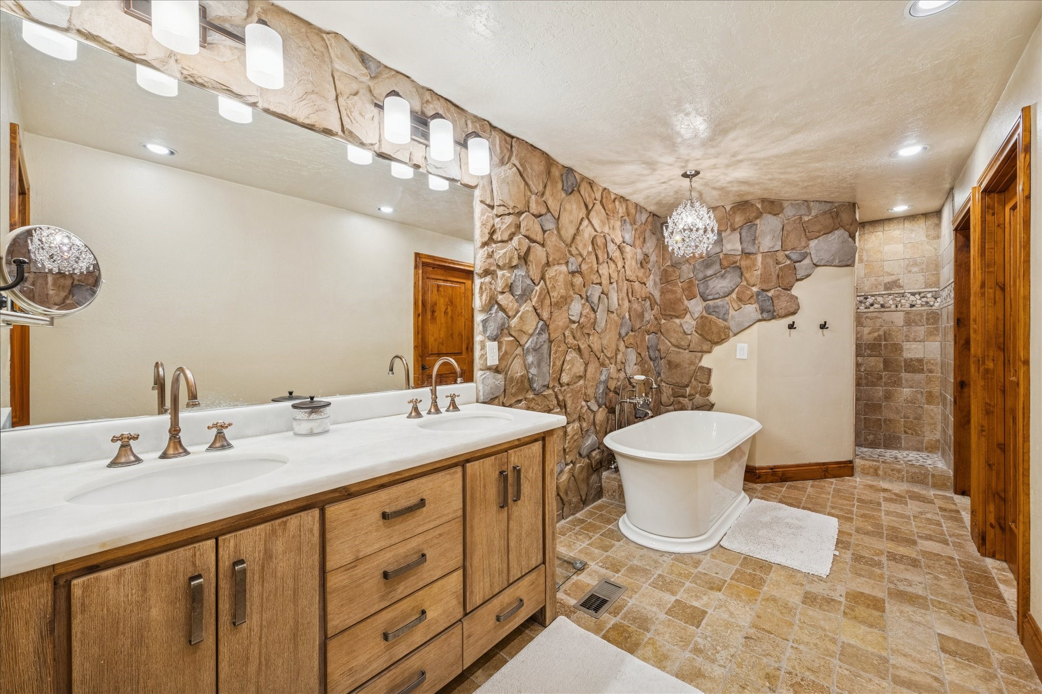 640 Piney Creek Road Bellville, TX 77418 - Photo 13 of 31 A large primary bathroom with a dramatic stone accent wall and double sinks.