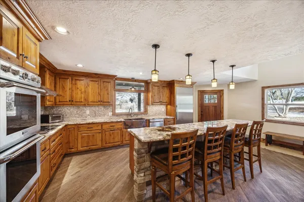 a view of a kitchen with kitchen island granite countertop wooden floors and a view of living room