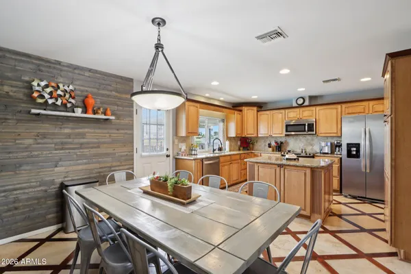 a kitchen with stainless steel appliances granite countertop a refrigerator a sink dishwasher a stove and white countertops with wooden floor