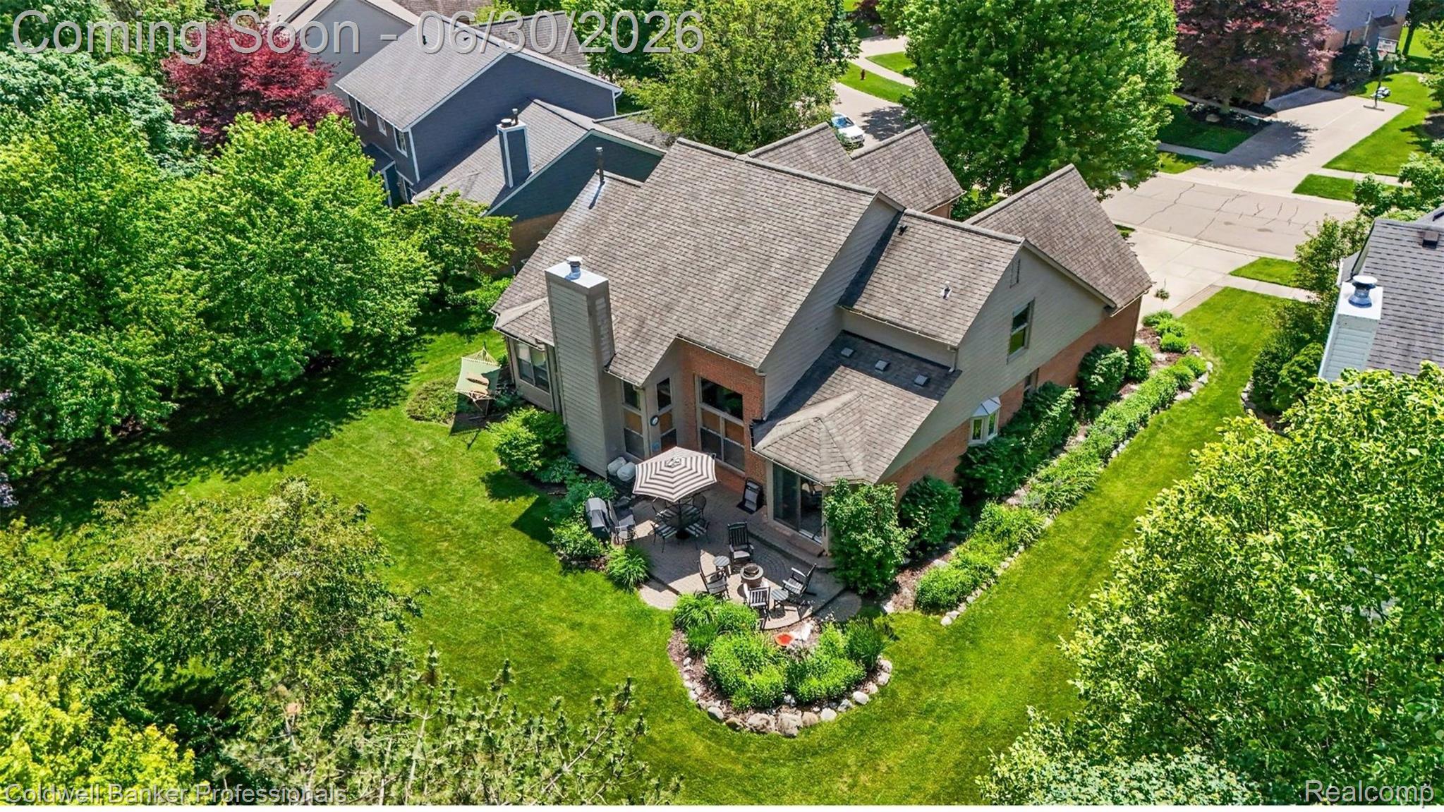 1085 Bloomview Circle Rochester, MI 48307 - Photo 58 of 67 Brick and siding exterior with a multi-level roofline, featuring a stone patio, extensive green lawn, and mature trees
