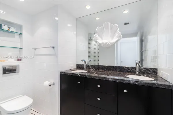 a bathroom with a granite countertop sink mirror and toilet