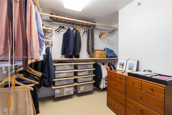 a view of walk in closet with clothes and shoes