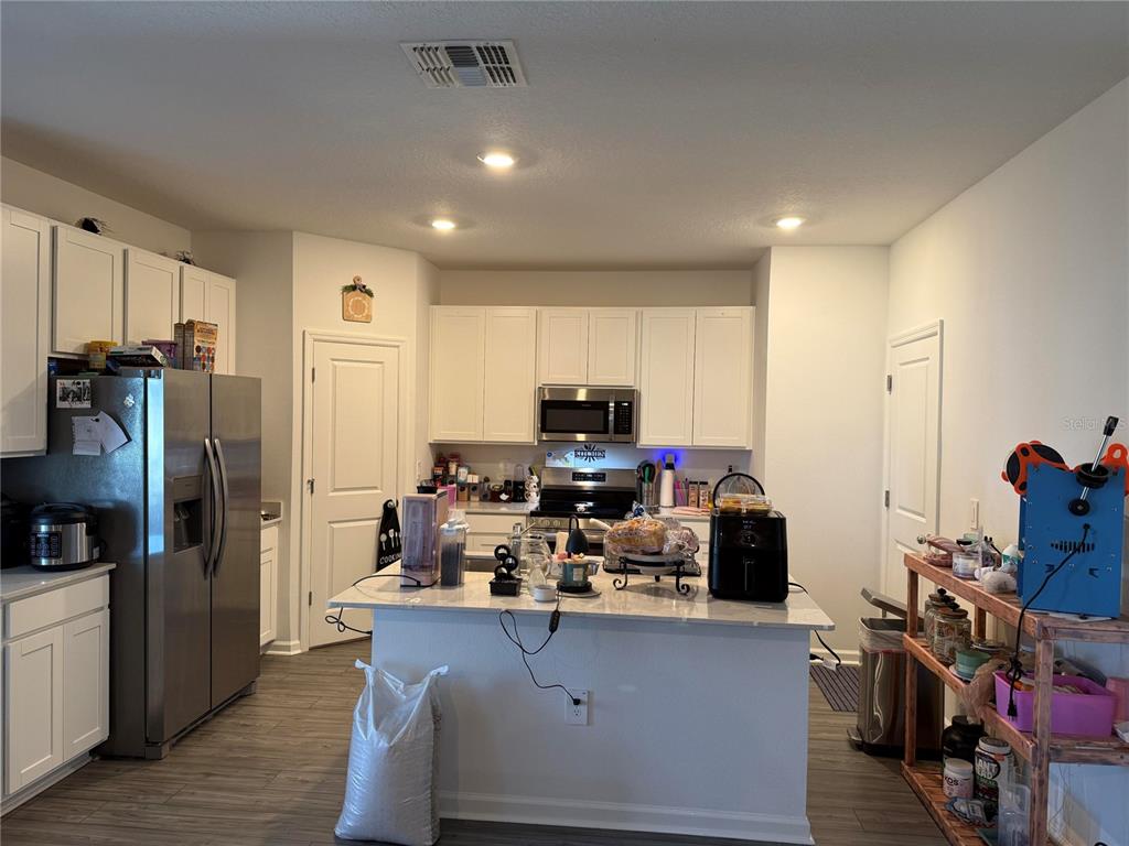 4682 Southwest 83rd Loop Ocala, FL 34476 - Photo 3 of 7 a kitchen with kitchen island a refrigerator wooden floor and a sink