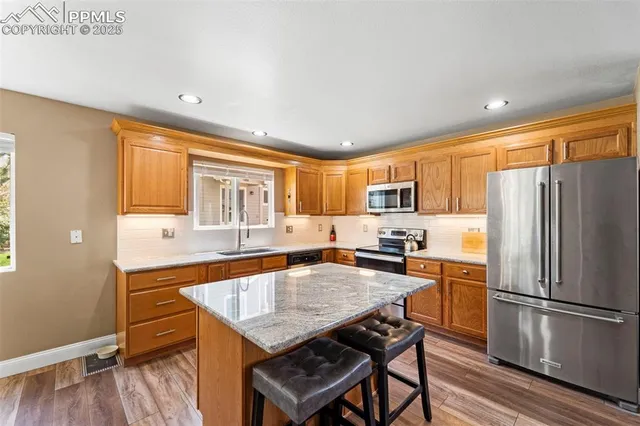 a kitchen with granite countertop a refrigerator a stove a sink dishwasher and a dining table with wooden floor