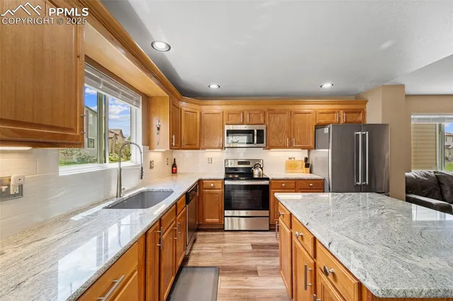 a kitchen with stainless steel appliances granite countertop a sink a stove and a refrigerator