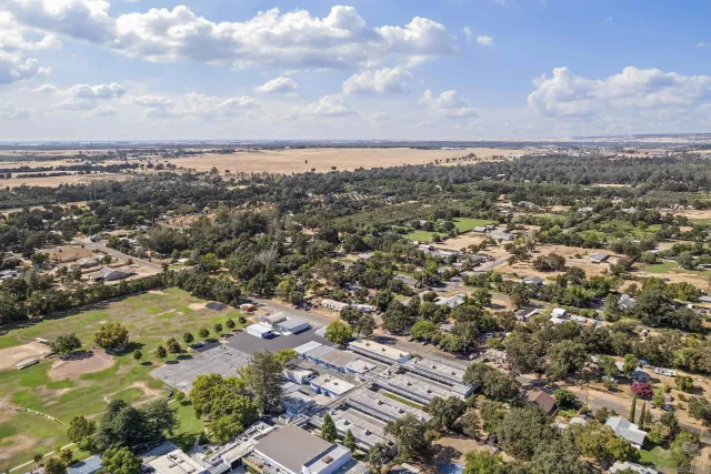 an aerial view of residential houses with outdoor space and trees