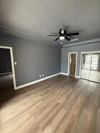a view of an empty room and chandelier fan and kitchen view