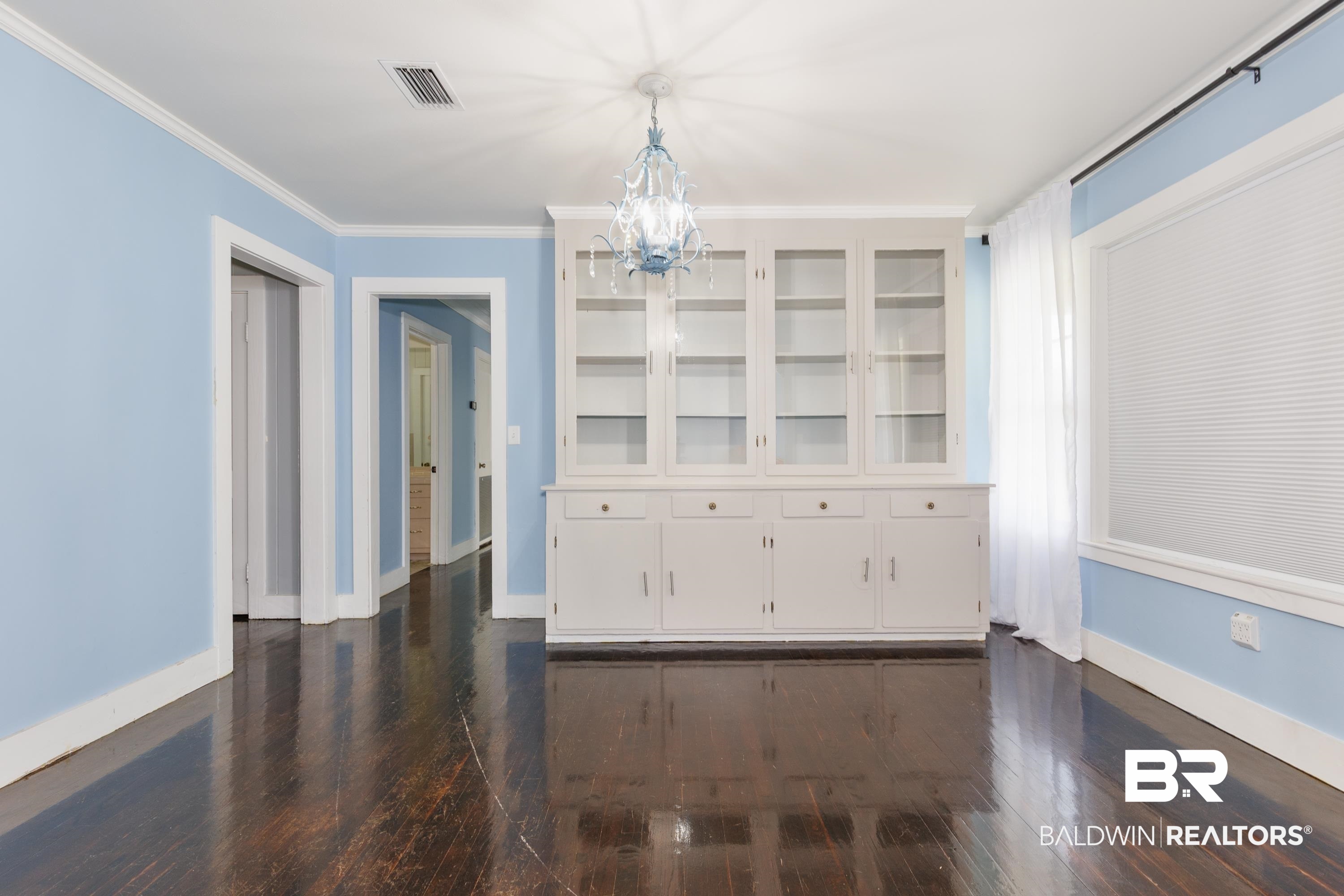 208 Beck Street Atmore, AL 36502 - Photo 12 of 26 Unfurnished dining area featuring dark wood-style flooring, a chandelier, and crown molding
