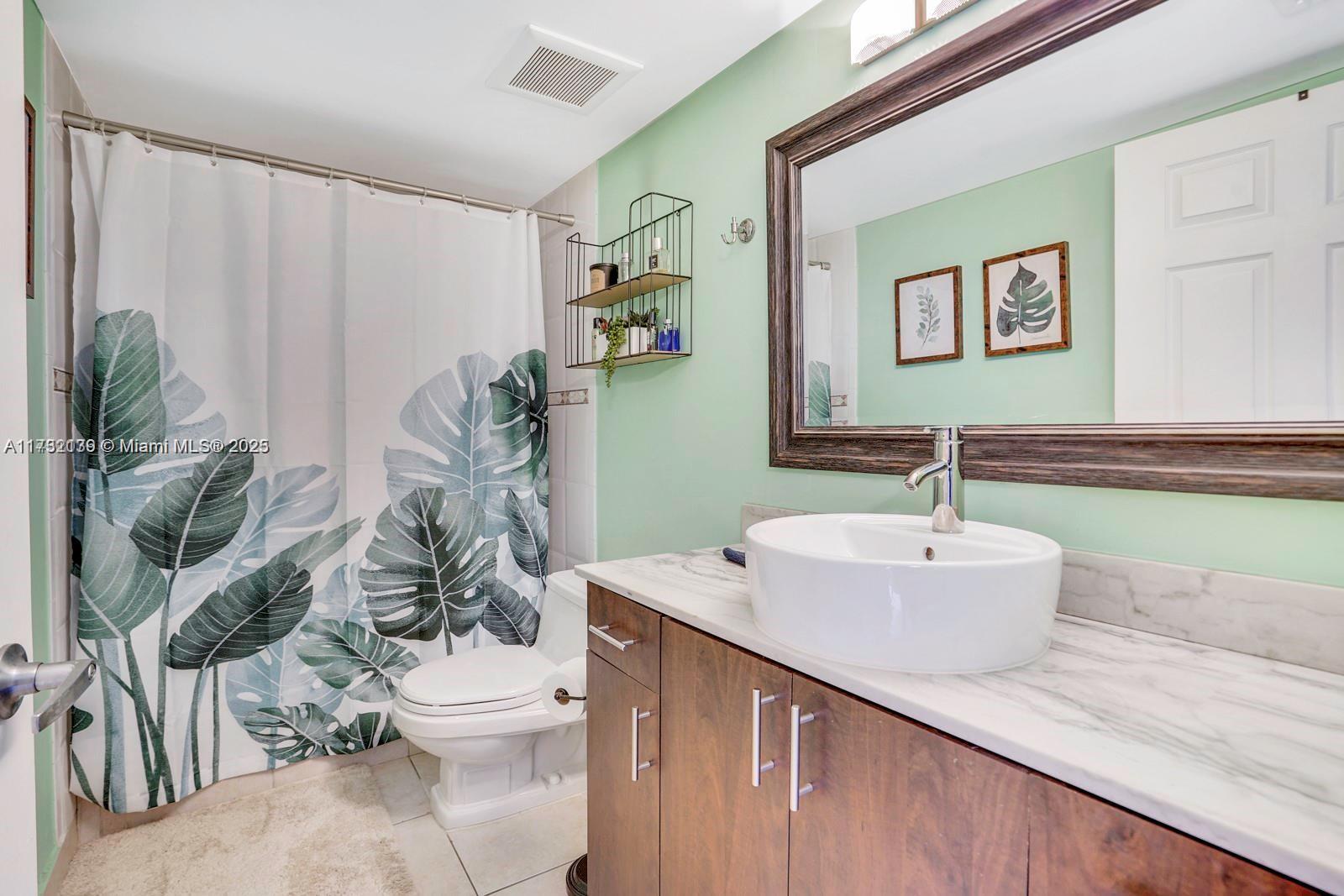 2475 Northwest 16th St Road, Unit 216 Miami, FL 33125 - Photo 14 of 16 a bathroom with a sink a toilet and a mirror