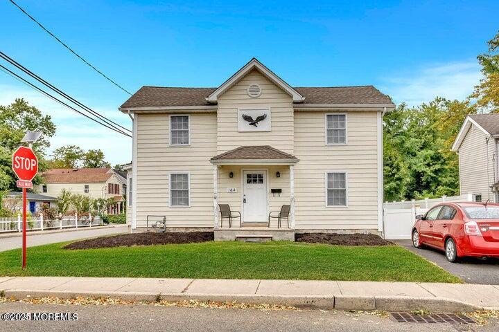 a view of a white house with a yard and a street