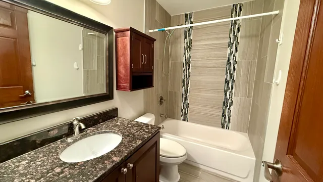 a bathroom with a granite countertop sink toilet a shower and a mirror