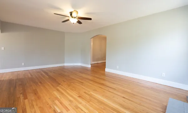 an empty room with wooden floor and ceiling fan