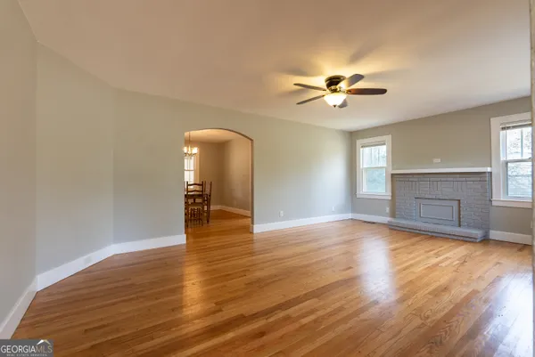 a view of empty room with wooden floor and fan