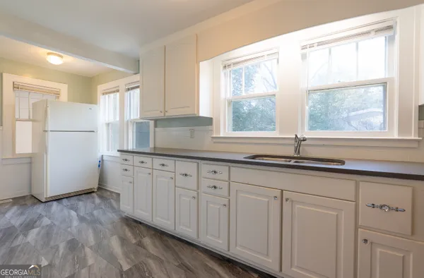 a kitchen with granite countertop white cabinets white appliances a sink and a window