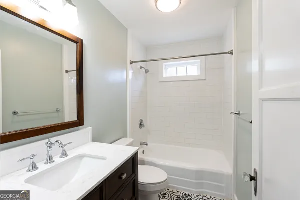 a bathroom with a bathtub shower sink vanity mirror and toilet