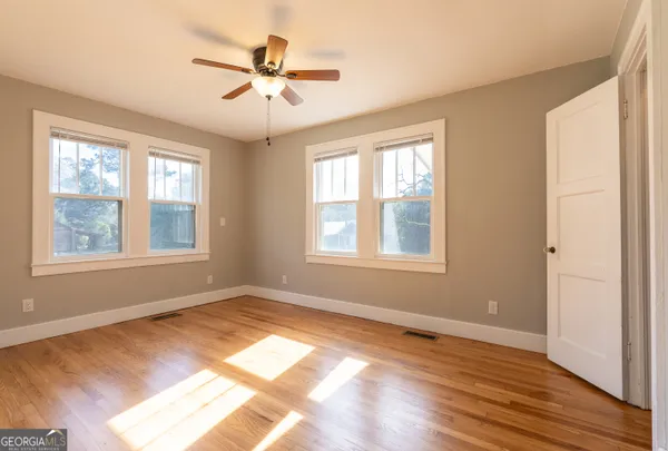 a view of an empty room with wooden floor and a window