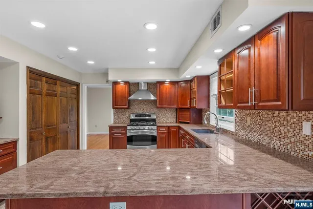 a kitchen with stainless steel appliances granite countertop wooden cabinets a stove and a sink