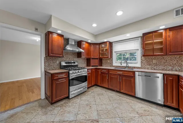 a kitchen with stainless steel appliances granite countertop a stove sink and cabinets