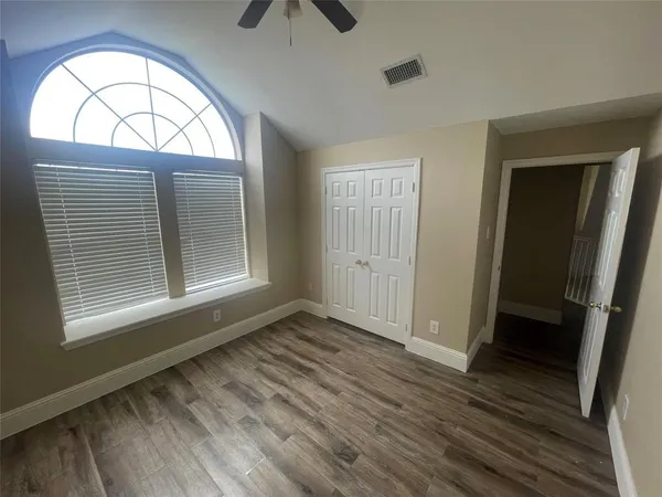 an empty room with wooden floor cabinet and windows