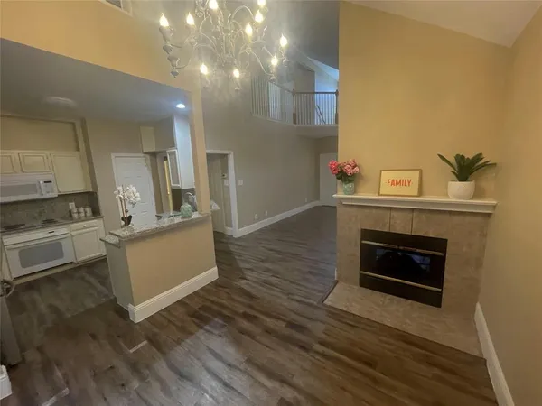 a view of kitchen and empty room with wooden floor