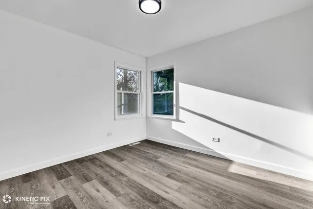 a view of an empty room with wooden floor and window