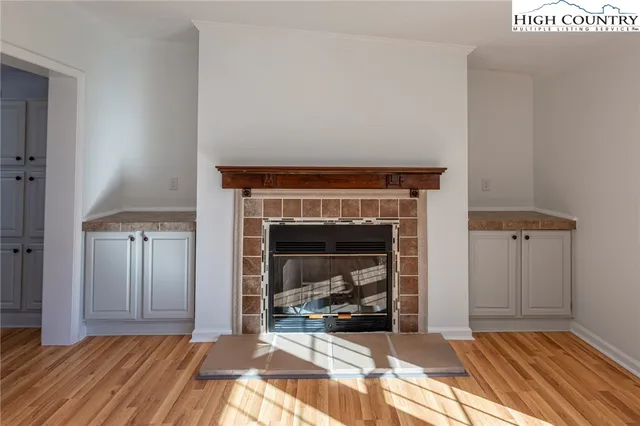 a view of a livingroom with wooden floor a fireplace and entryway
