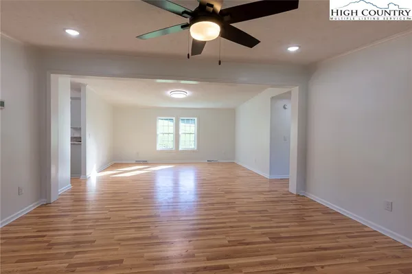 a view of empty room with wooden floor and fan