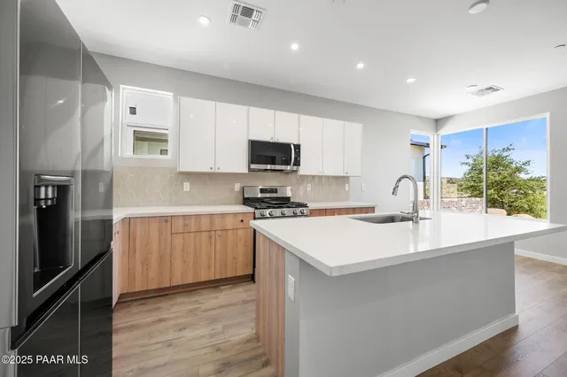 a large kitchen with stainless steel appliances a refrigerator stove microwave and sink