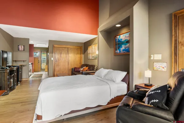 a spacious bedroom with a bed and wooden floor