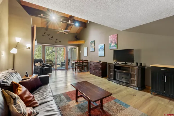 a living room with furniture a flat screen tv and kitchen view