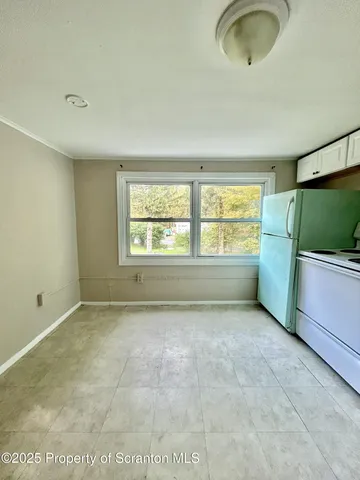 a view of an empty room with a window and kitchen area