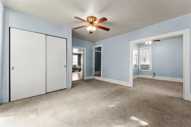 an empty room with closet and a chandelier fan