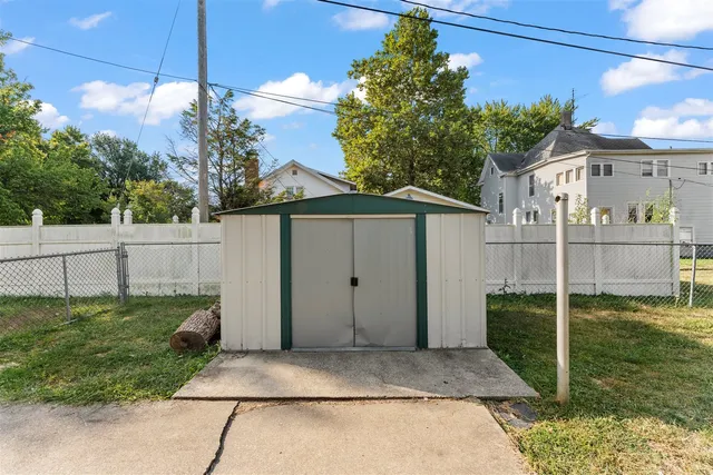 a view of a barn house next to a yard with wooden fence