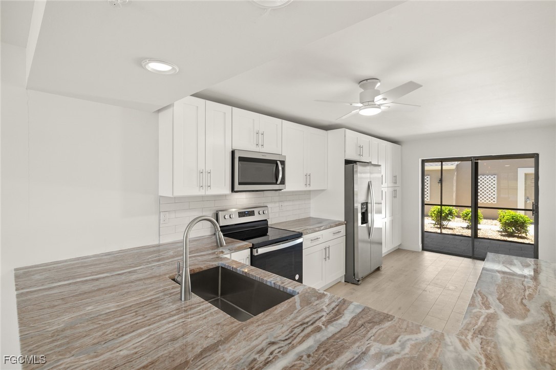 16260 Kelly Cove Drive, Unit 235 Fort Myers, FL 33908 - Photo 11 of 30 a kitchen with granite countertop a stove top oven a refrigerator a sink and dishwasher with wooden floor