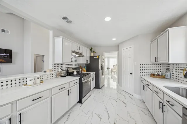 a kitchen with granite countertop a sink stove and refrigerator