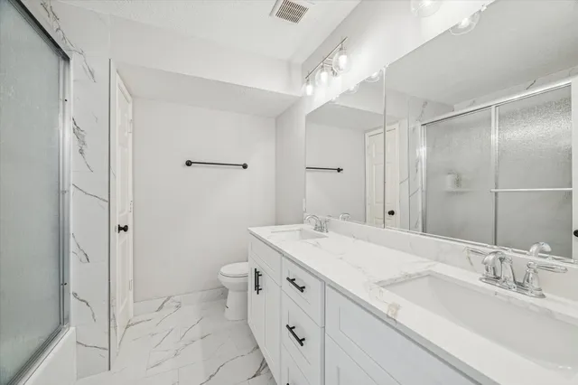 a spacious bathroom with a granite countertop sink a toilet and shower
