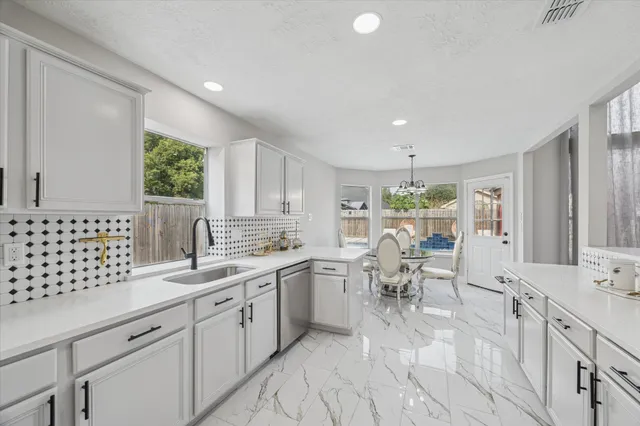 a large white kitchen with lots of counter space dining table and chairs