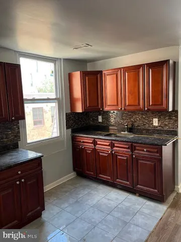 a kitchen with granite countertop a sink window and cabinets